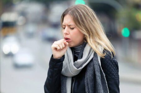 Shot of illness young woman coughing in the street.